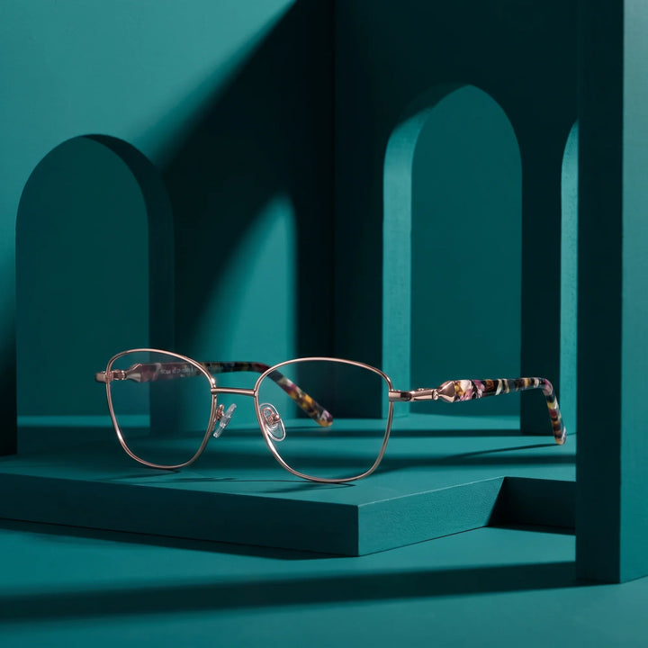 Anteojos Fiore 2208 en brown gold – staged on a sculptural teal architecture set