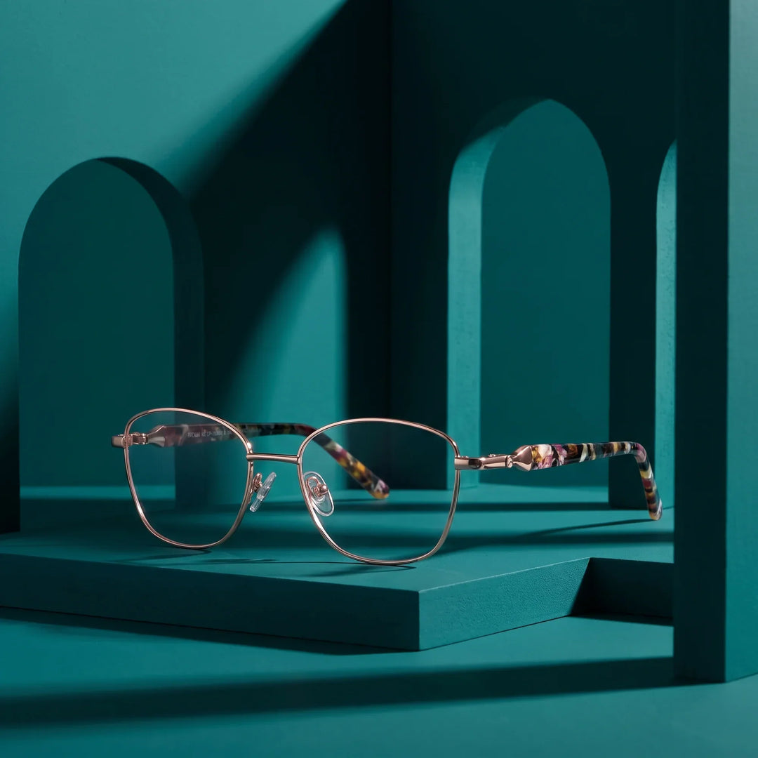 Anteojos Fiore 2208 en café dorado – staged on a sculptural teal architecture set