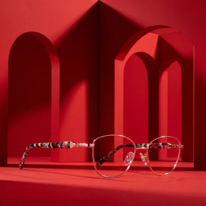Anteojos Fiore 2208 en brown gold – displayed on a vivid red podium among arches