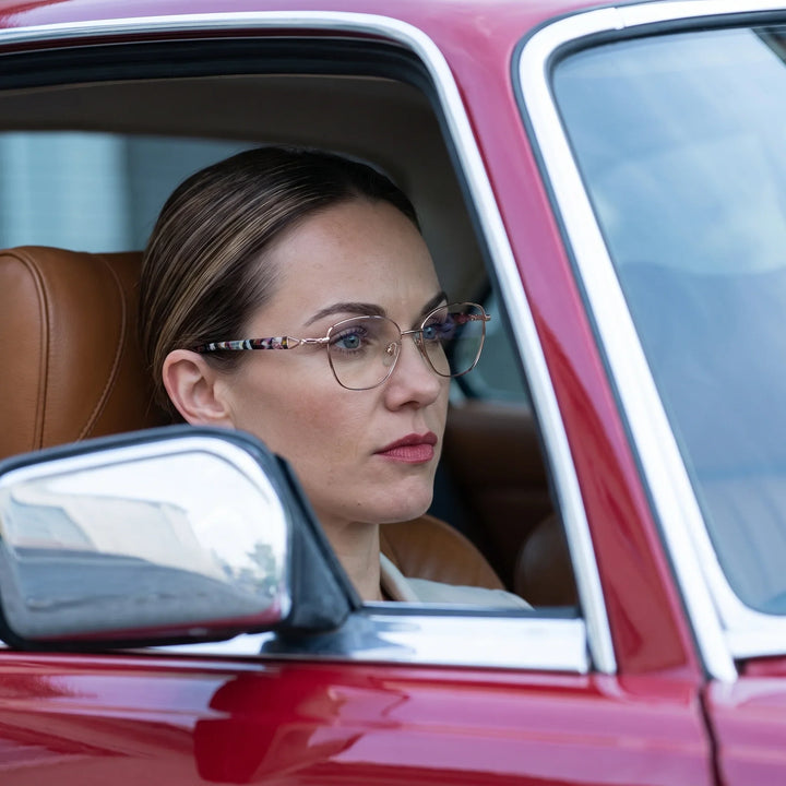 Anteojos Fiore 2208 en brown gold, en modelo – retrato de campaña, mirada a través de la ventana de un auto clásico rojo
