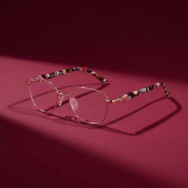 Anteojos Fiore 2208 en brown gold – editorial still life on a saturated burgundy set