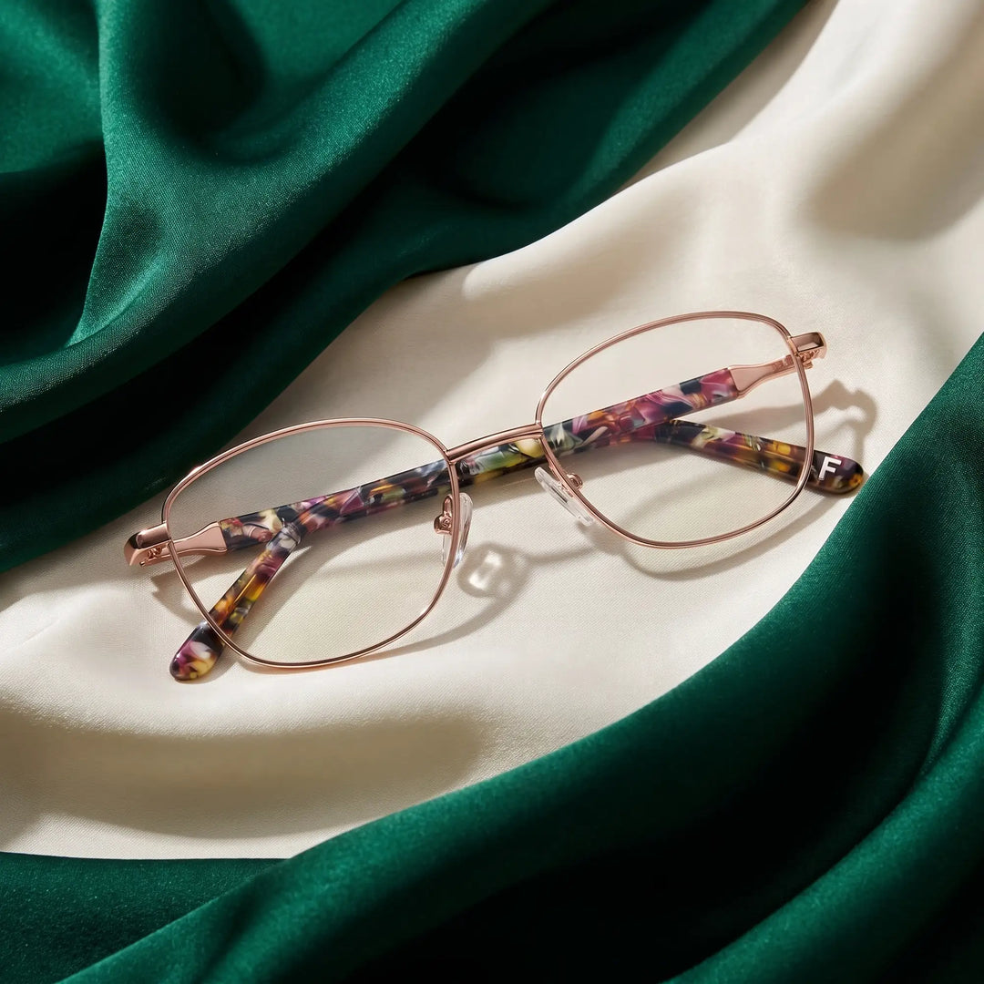 Anteojos Fiore 2208 en brown gold – resting on draped emerald and ivory silk