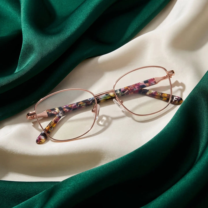 Anteojos Fiore 2208 en brown gold – resting on draped emerald and ivory silk