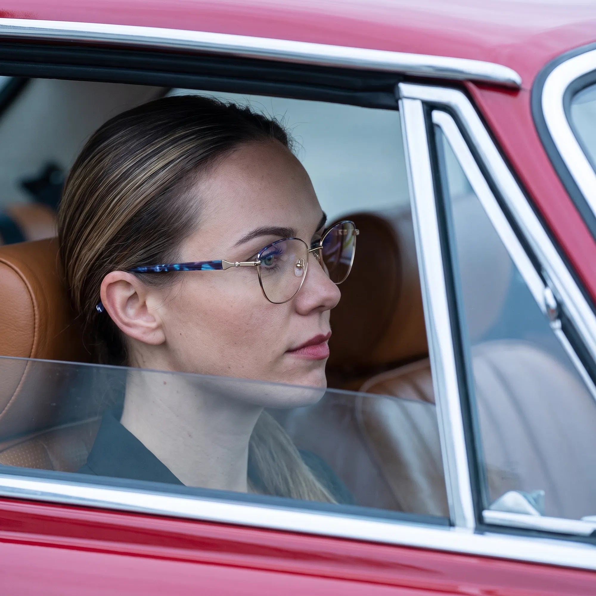 Anteojos Fiore 2208 en gun blue, en modelo – retrato de campaña, mirada a través de la ventana de un auto clásico rojo
