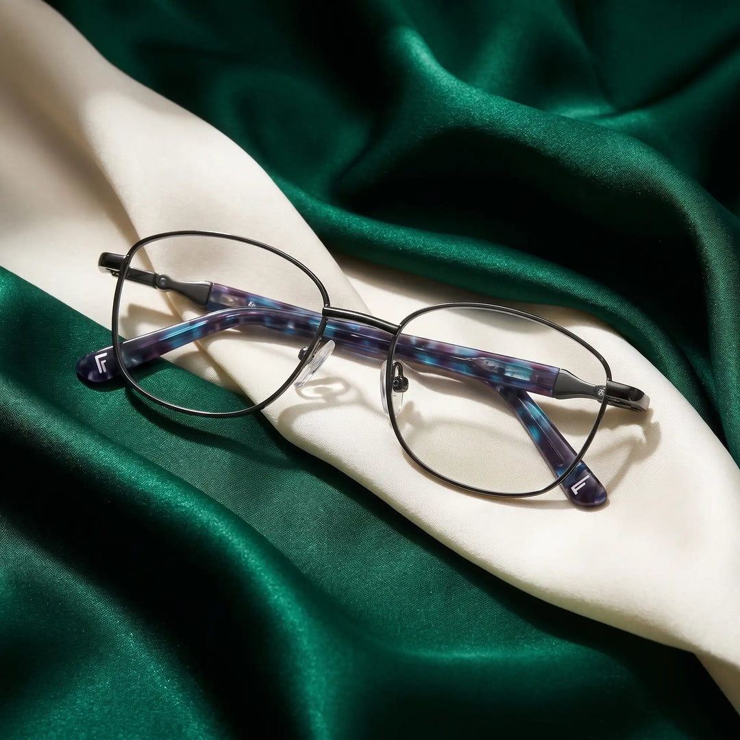 Anteojos Fiore 2208 en gun blue – resting on draped emerald and ivory silk