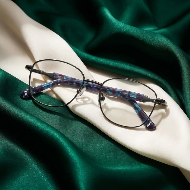 Anteojos Fiore 2208 en gun blue – resting on draped emerald and ivory silk