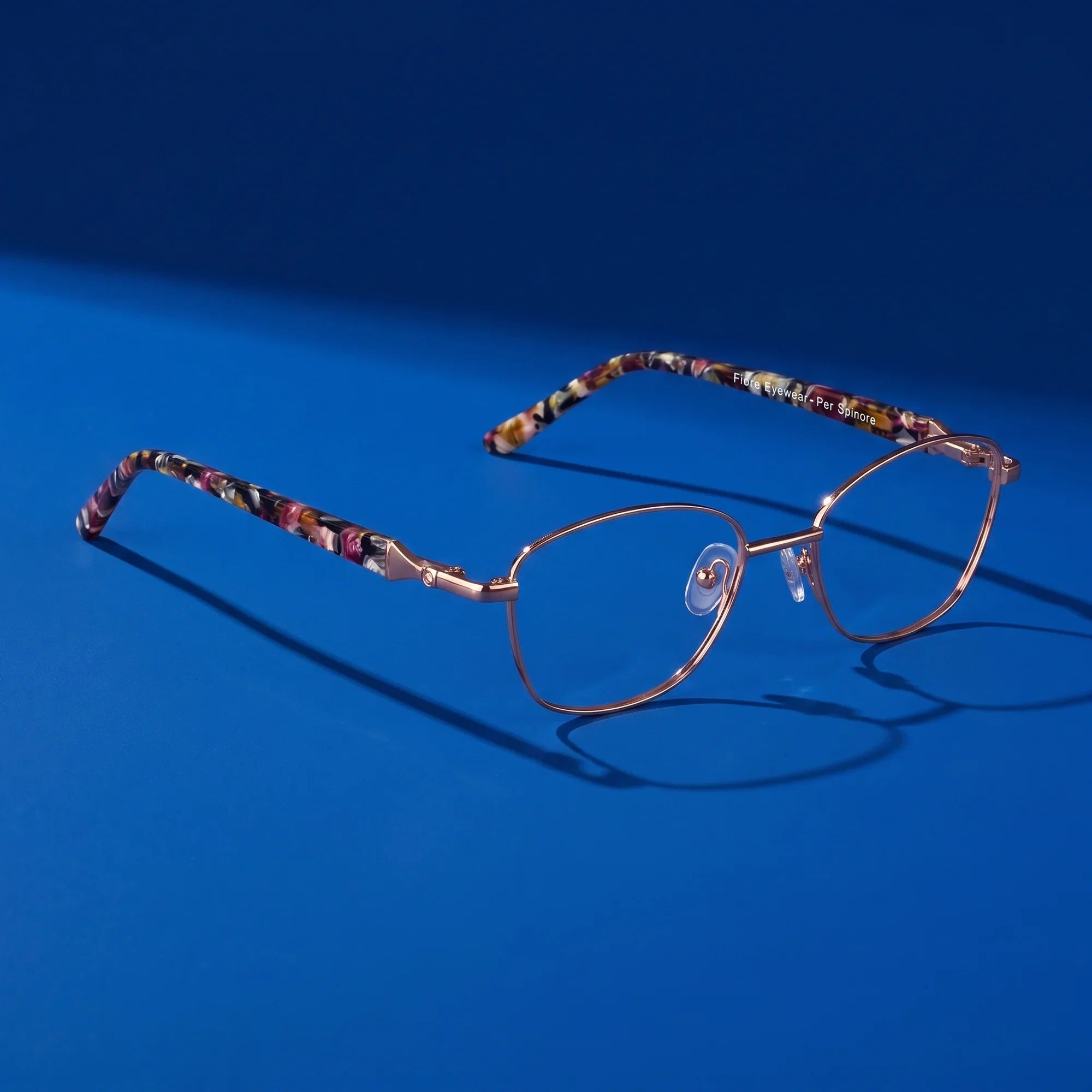 Anteojos Fiore 2208 en brown tortoiseshell – hero still life against a deep cobalt backdrop