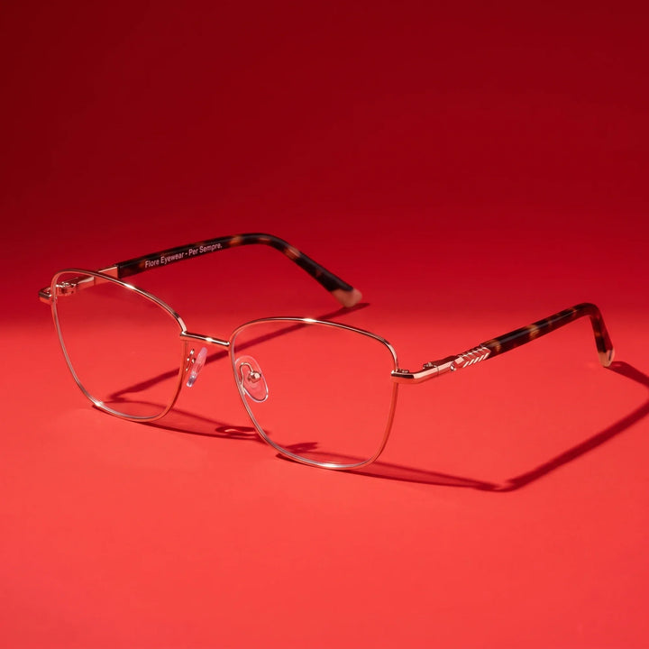 Anteojos Fiore 2210 en dorado rosado – hero still life against a deep vivid red backdrop