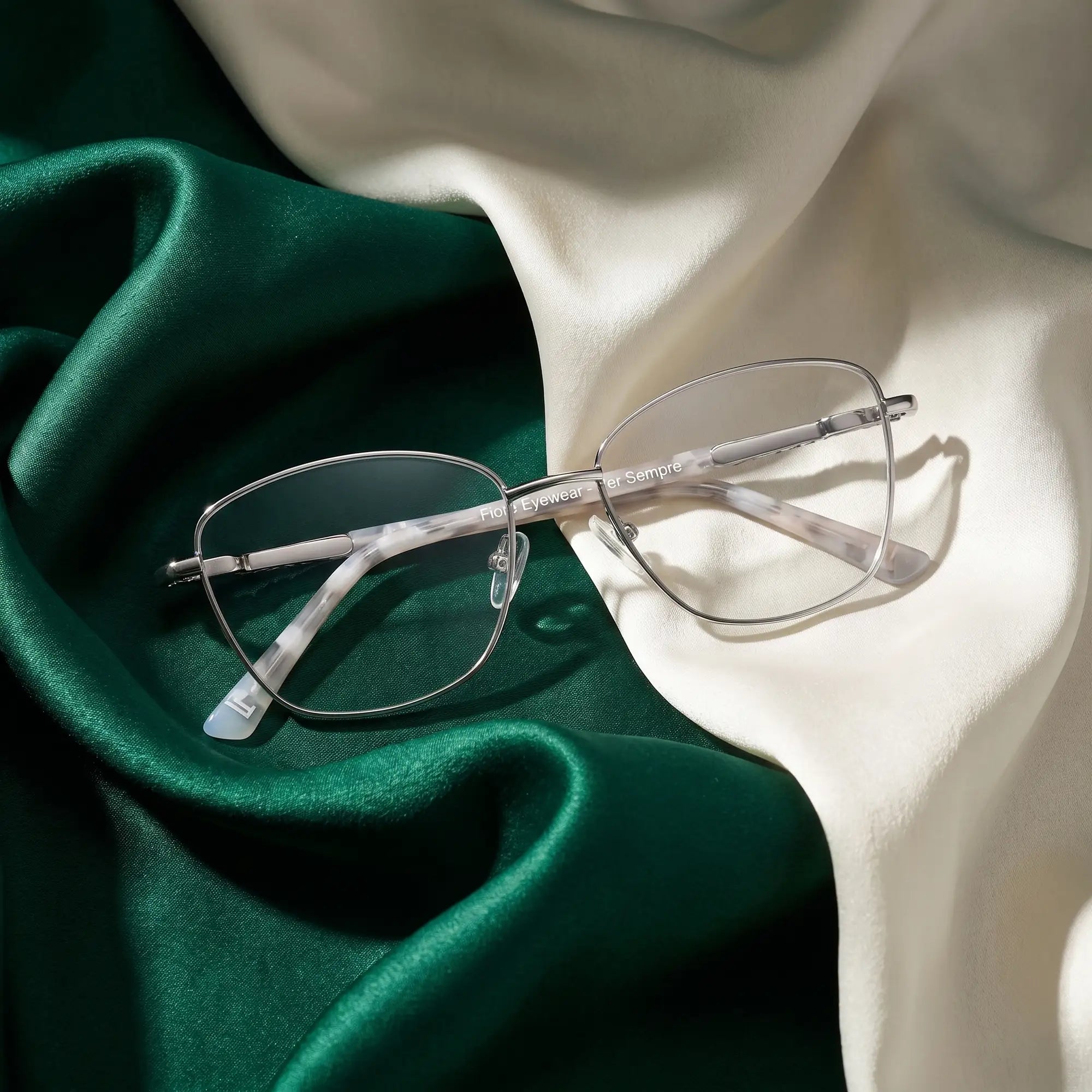 Anteojos Fiore 2210 en silver black – resting on draped emerald and ivory silk