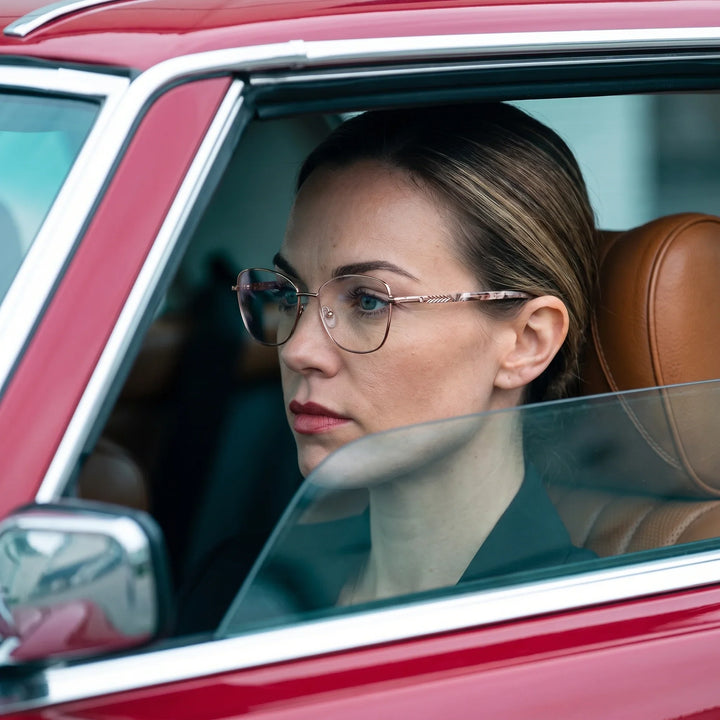 Anteojos Fiore 2210 en gold brown, en modelo – retrato de campaña, mirada a través de la ventana de un auto clásico rojo