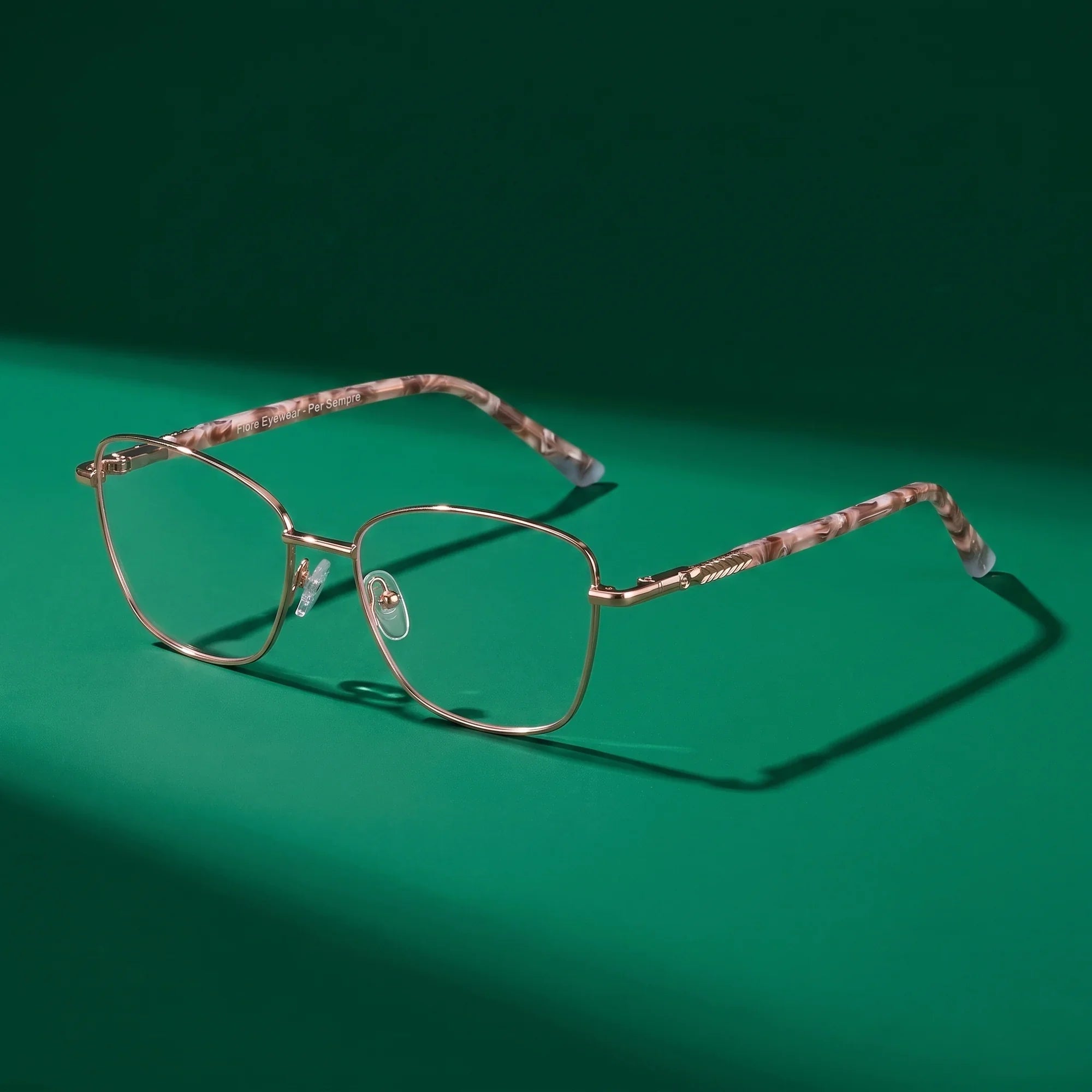 Anteojos Fiore 2210 en gold brown – bodegón editorial sobre un set esmeralda saturado