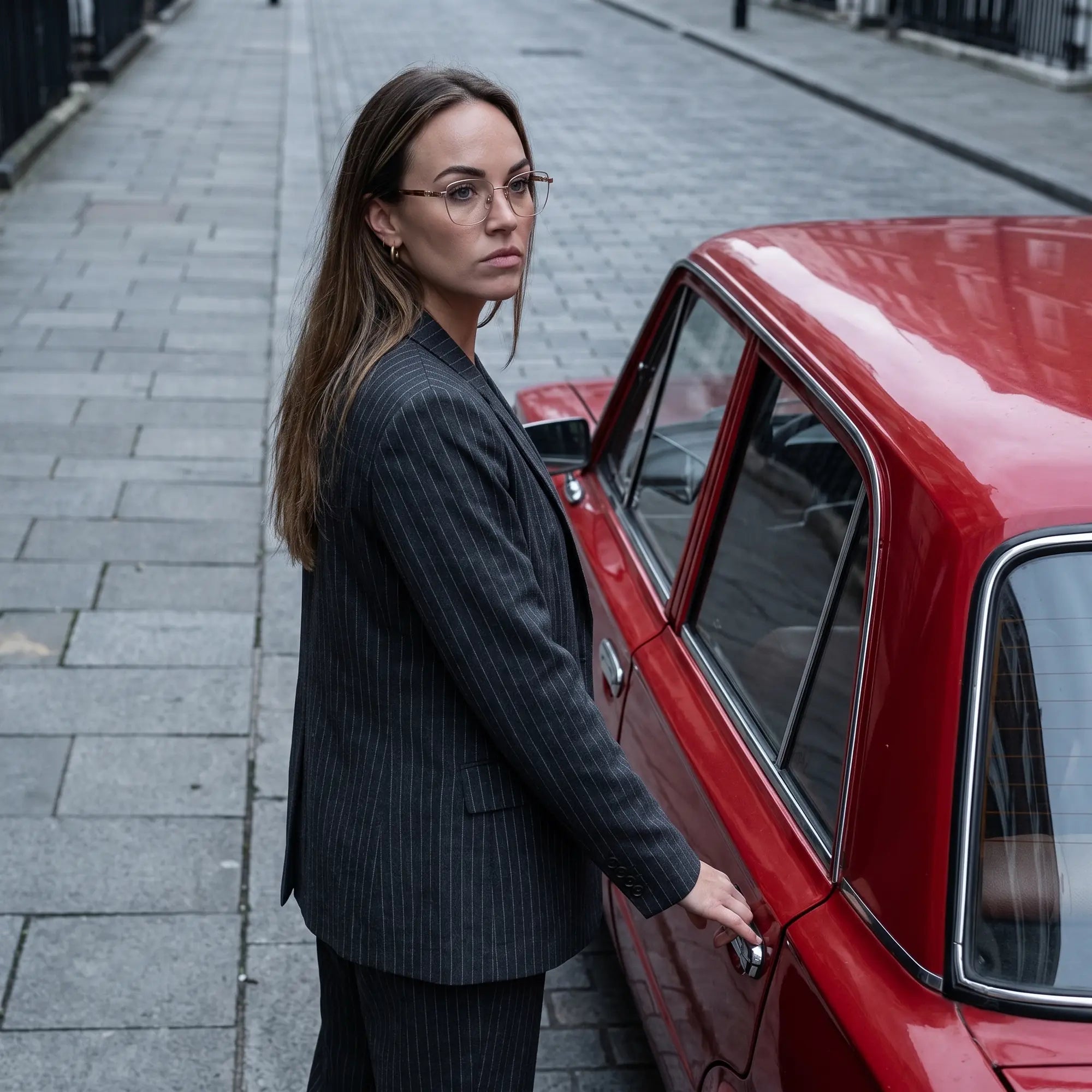 Anteojos Fiore 22115 en café, en modelo – retrato de campaña, traje a rayas junto a un auto clásico rojo