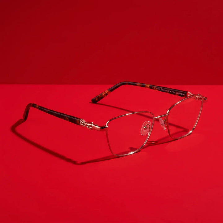 Anteojos Fiore 22115 en café – hero still life against a deep vivid red backdrop