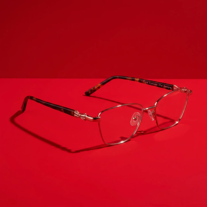 Anteojos Fiore 22115 en café – hero still life against a deep vivid red backdrop