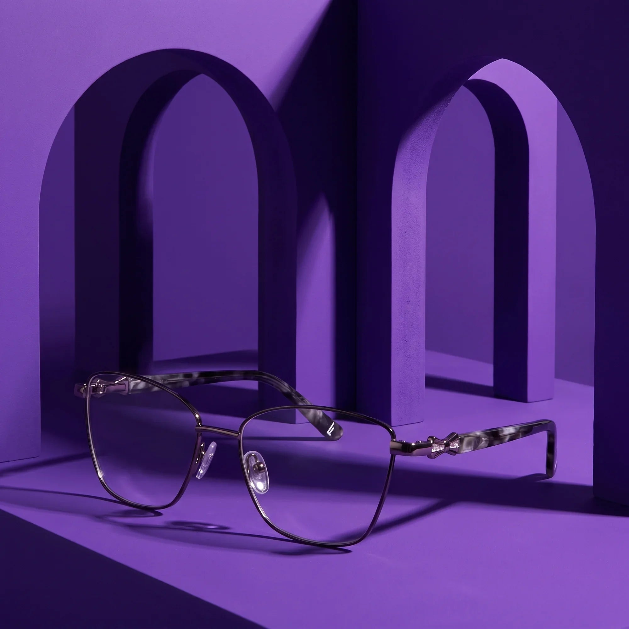 Anteojos Fiore 22115 en black silver – displayed on a violet podium among arches