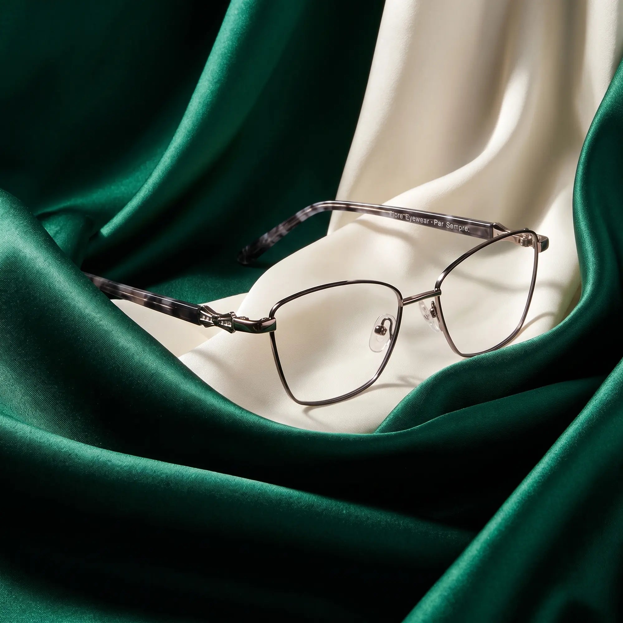 Anteojos Fiore 22115 en black silver – resting on draped emerald and ivory silk