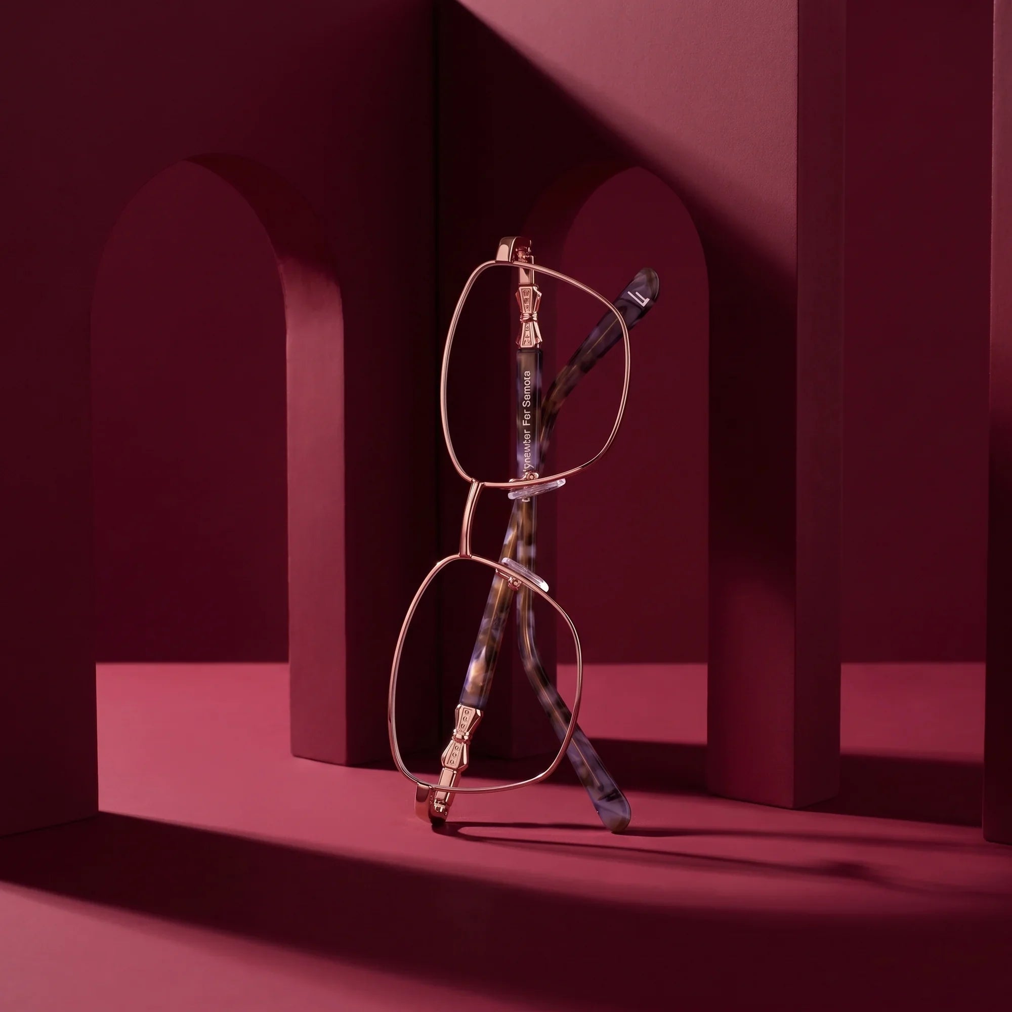 Anteojos Fiore 22115 en gold – staged on a sculptural burgundy architecture set