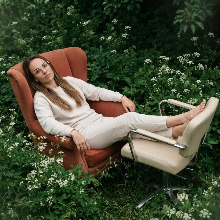 Anteojos Fiore 3837 en pink gold, en modelo – retrato de campaña, lounging in an armchair in a wildflower meadow