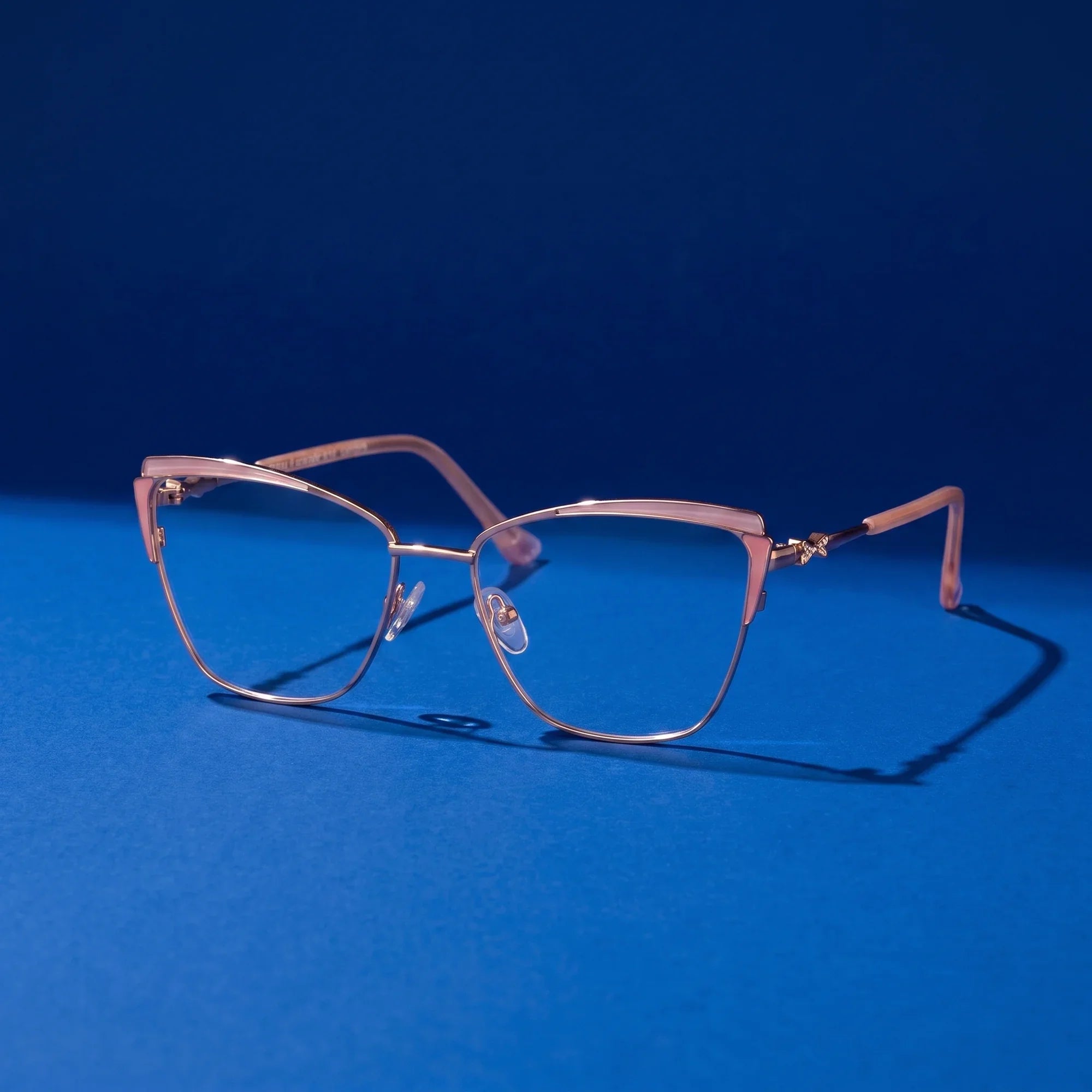 Anteojos Fiore 3837 en pink gold – bodegón sobre fondo cobalto de estudio