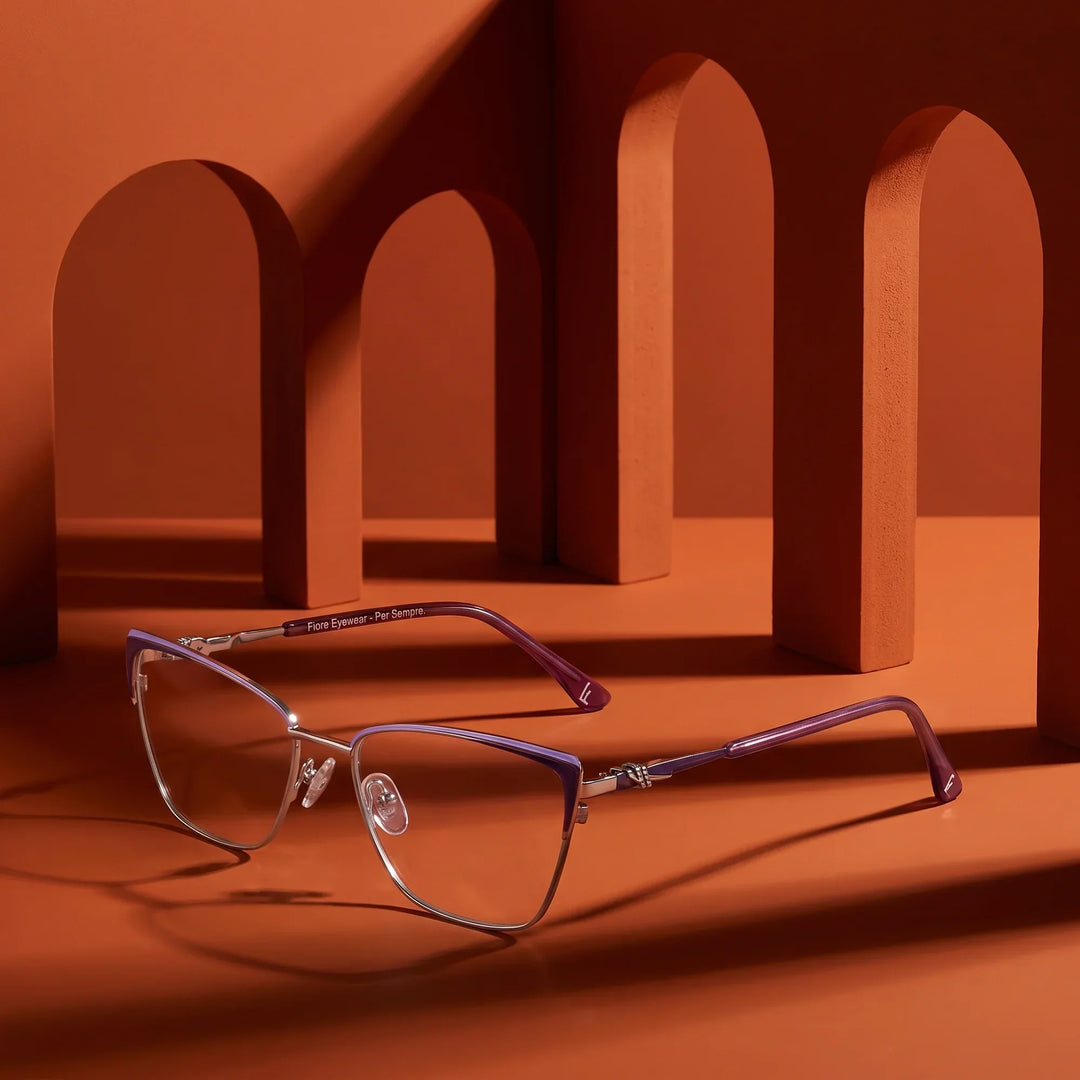 Anteojos Fiore 3839 en morado plateado – displayed on a burnt orange podium among arches