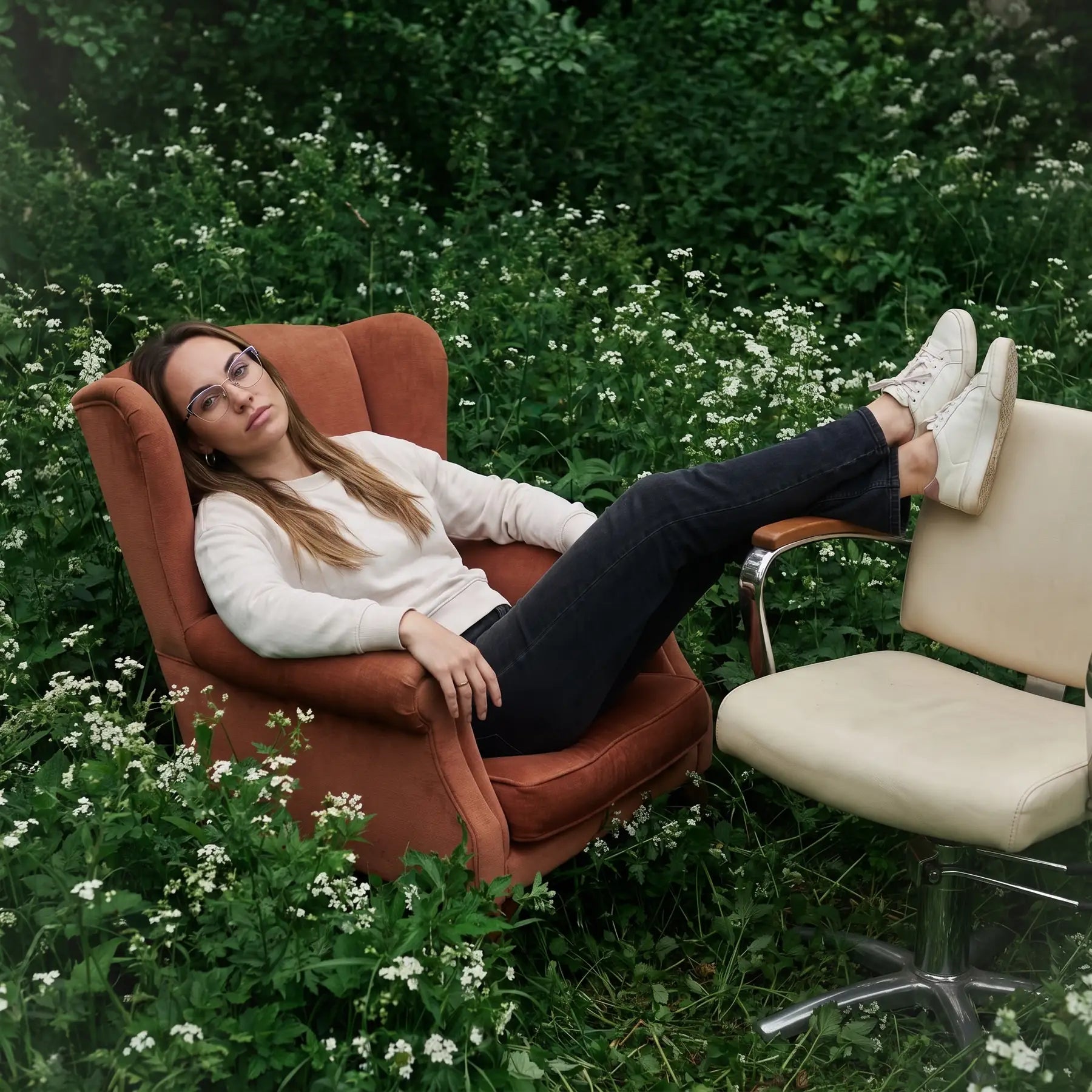 Anteojos Fiore 3839 en purple silver, en modelo – retrato de campaña, lounging in an armchair in a wildflower meadow