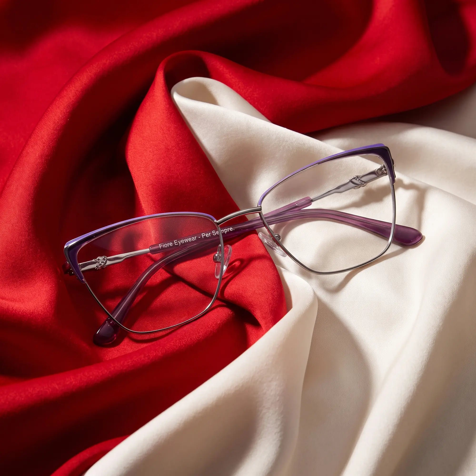 Anteojos Fiore 3839 en purple silver – resting on draped vivid red and ivory silk