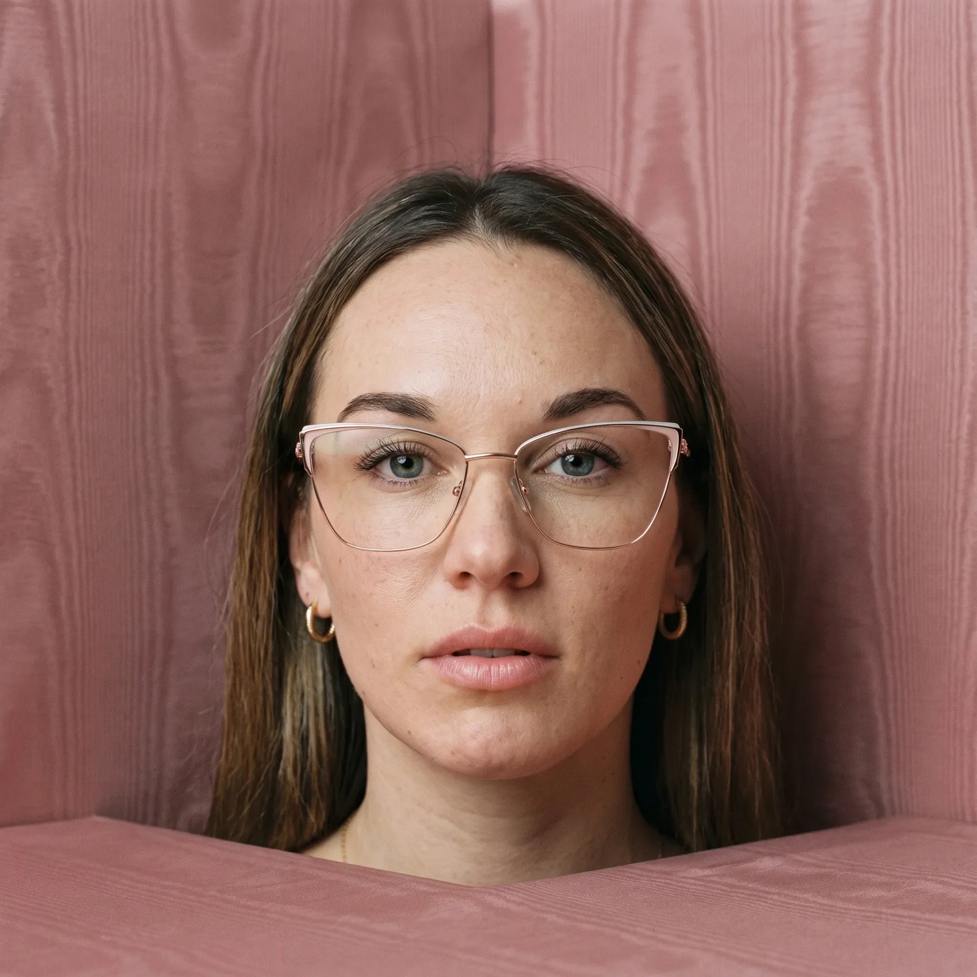 Anteojos Fiore 3839 en pink gold, en modelo – retrato de campaña, face framed by rose moire upholstery