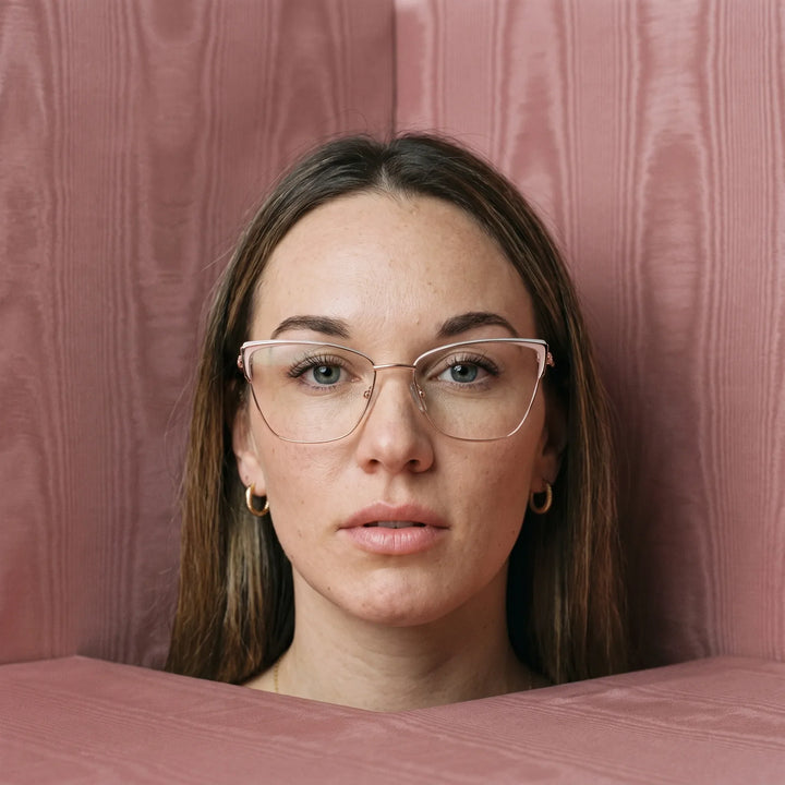 Anteojos Fiore 3839 en pink gold, en modelo – retrato de campaña, face framed by rose moire upholstery