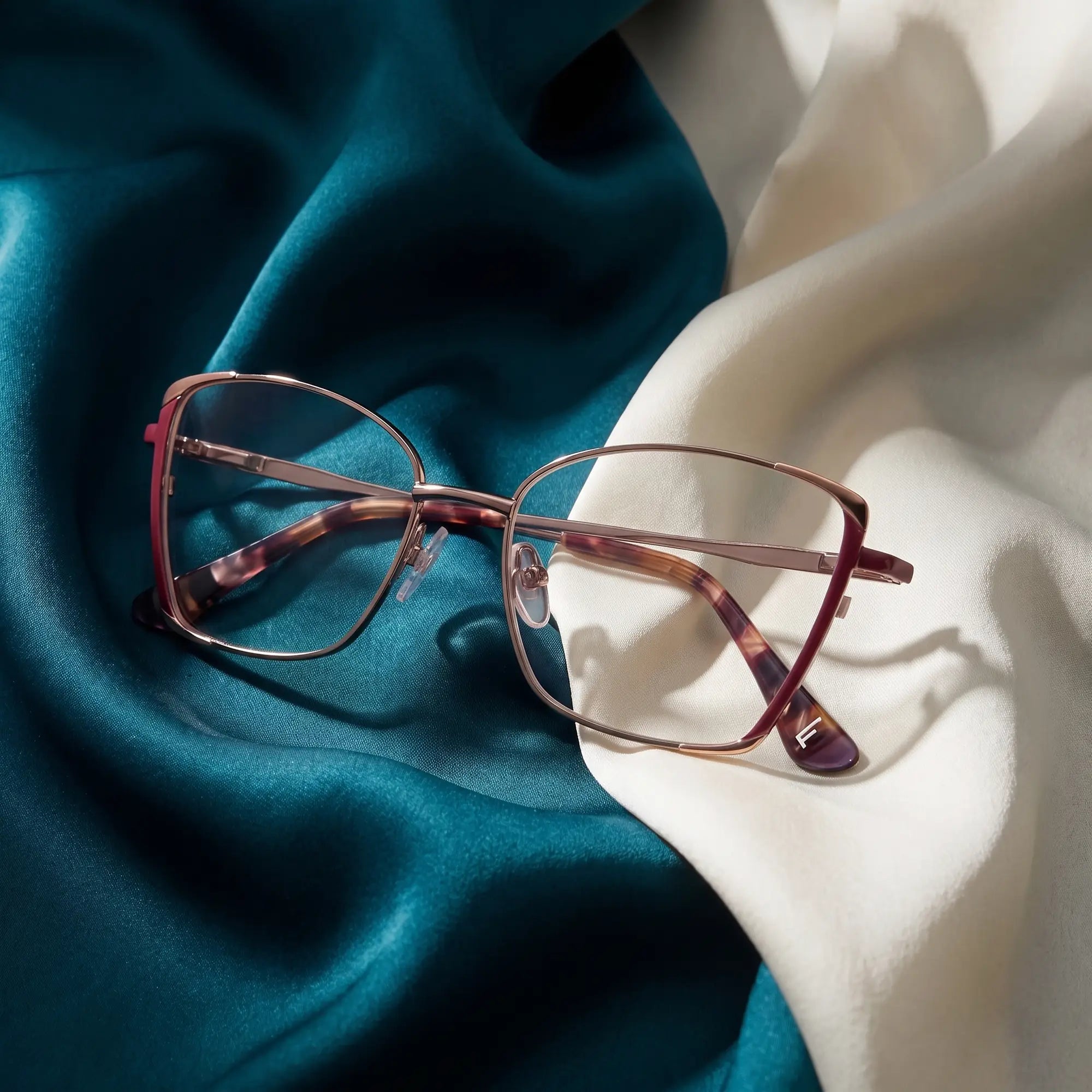 Anteojos Fiore 3916 en purple pink silver – resting on draped teal and ivory silk