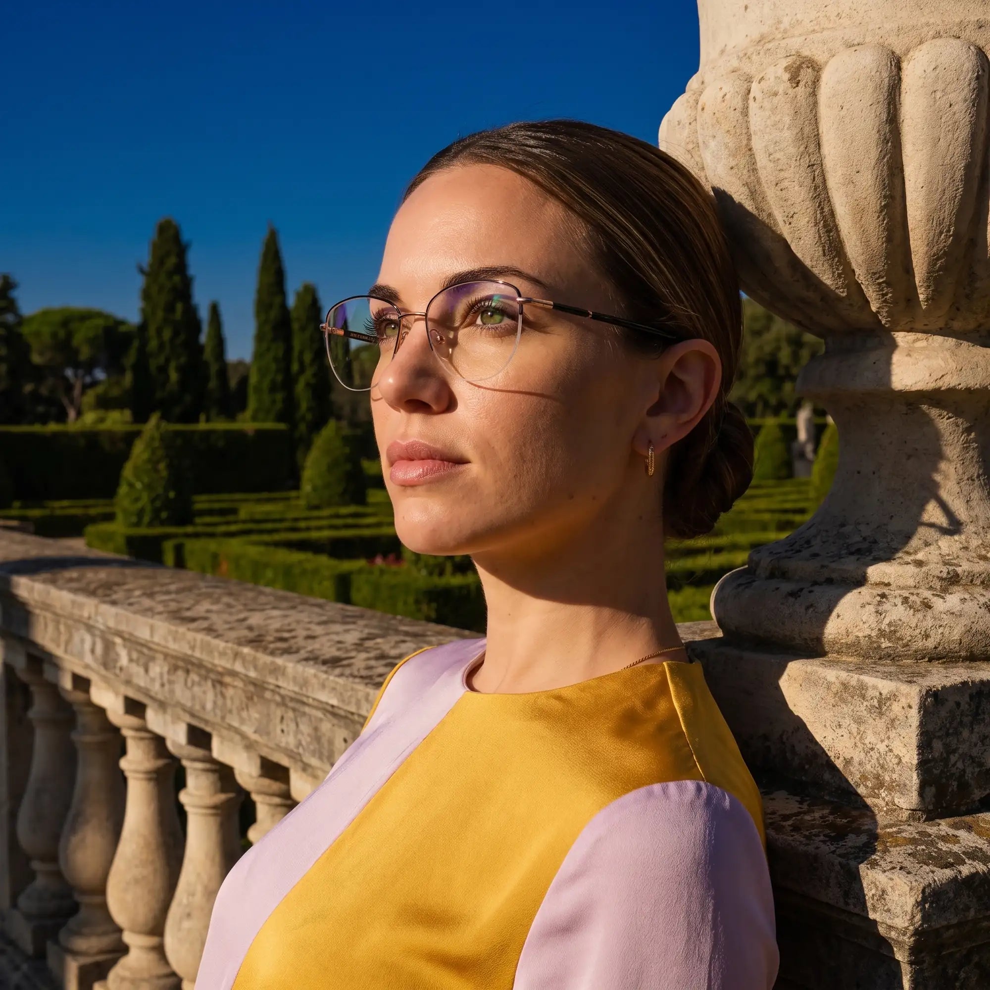 Anteojos Fiore 3921 en black gold, en modelo – retrato de campaña, luz de atardecer sobre un jardín de cipreses