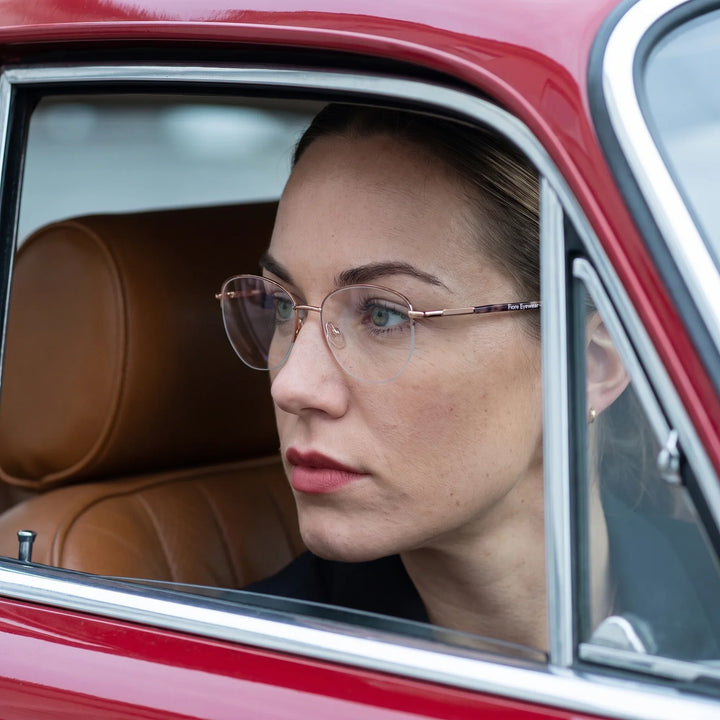 Anteojos Fiore 3921 en brown gold, en modelo – retrato de campaña, mirada a través de la ventana de un auto clásico rojo
