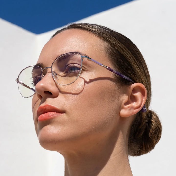 Anteojos Fiore 3921 en morado plateado, en modelo – retrato de campaña, cal balear al sol y cielo azul profundo