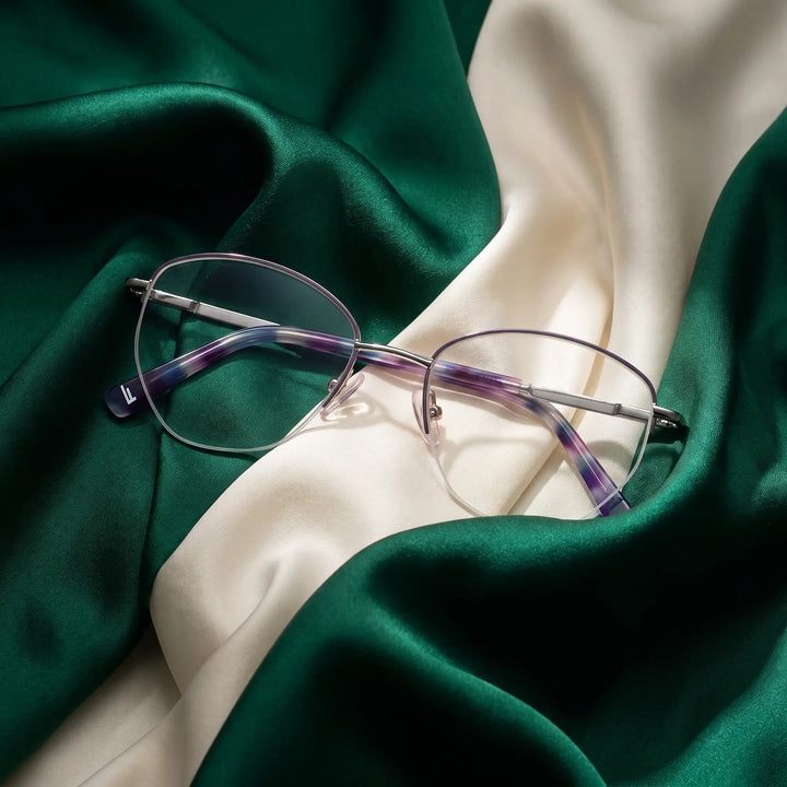 Anteojos Fiore 3921 en morado plateado – resting on draped emerald and ivory silk