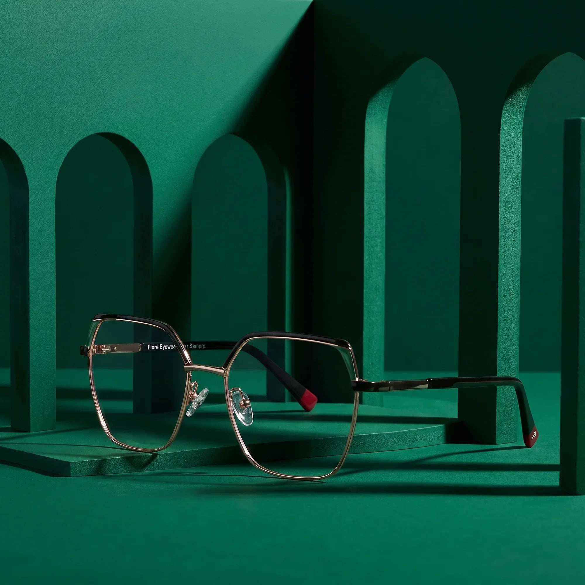 Anteojos Fiore 3971 en black gold – staged on a sculptural emerald architecture set