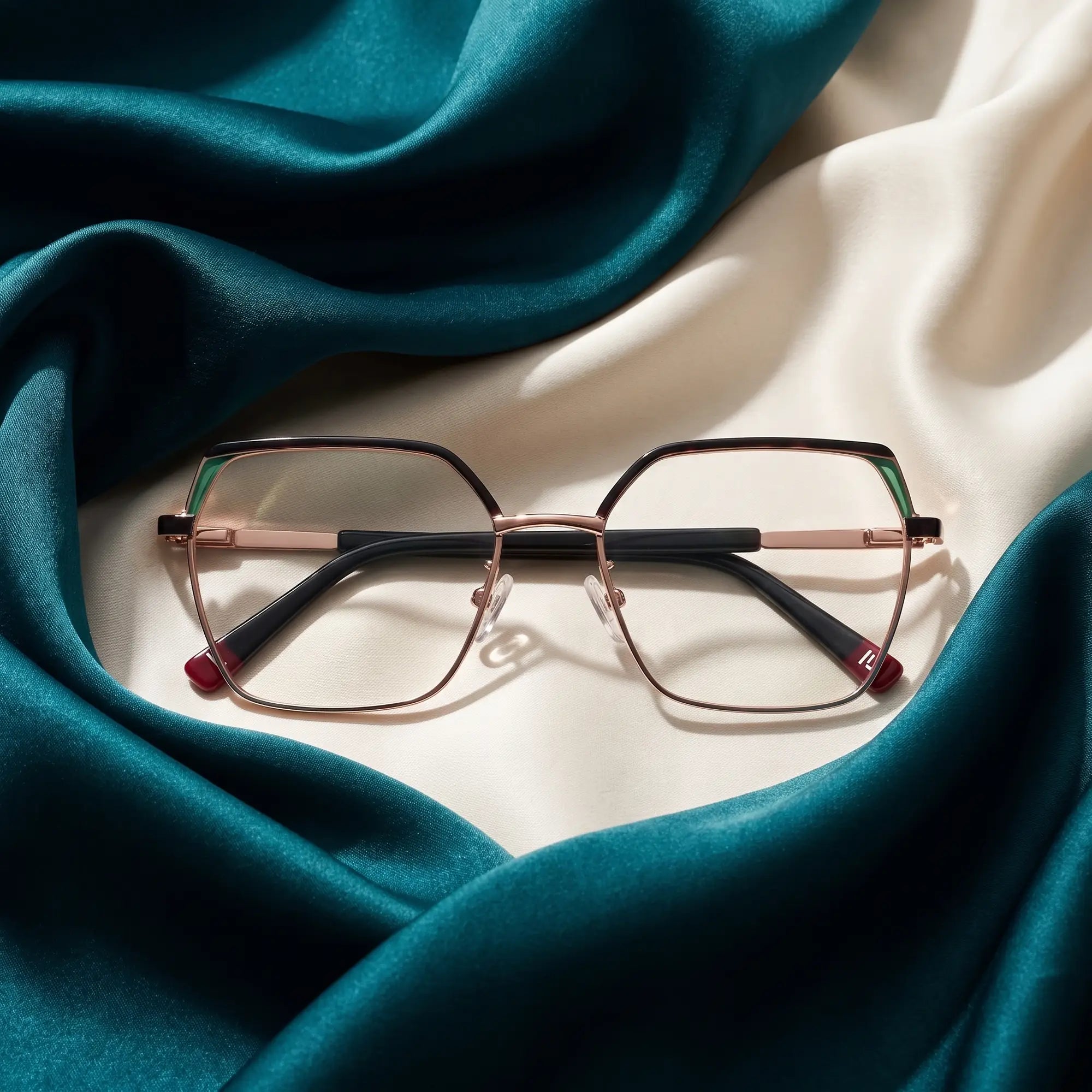 Anteojos Fiore 3971 en black gold – resting on draped teal and ivory silk