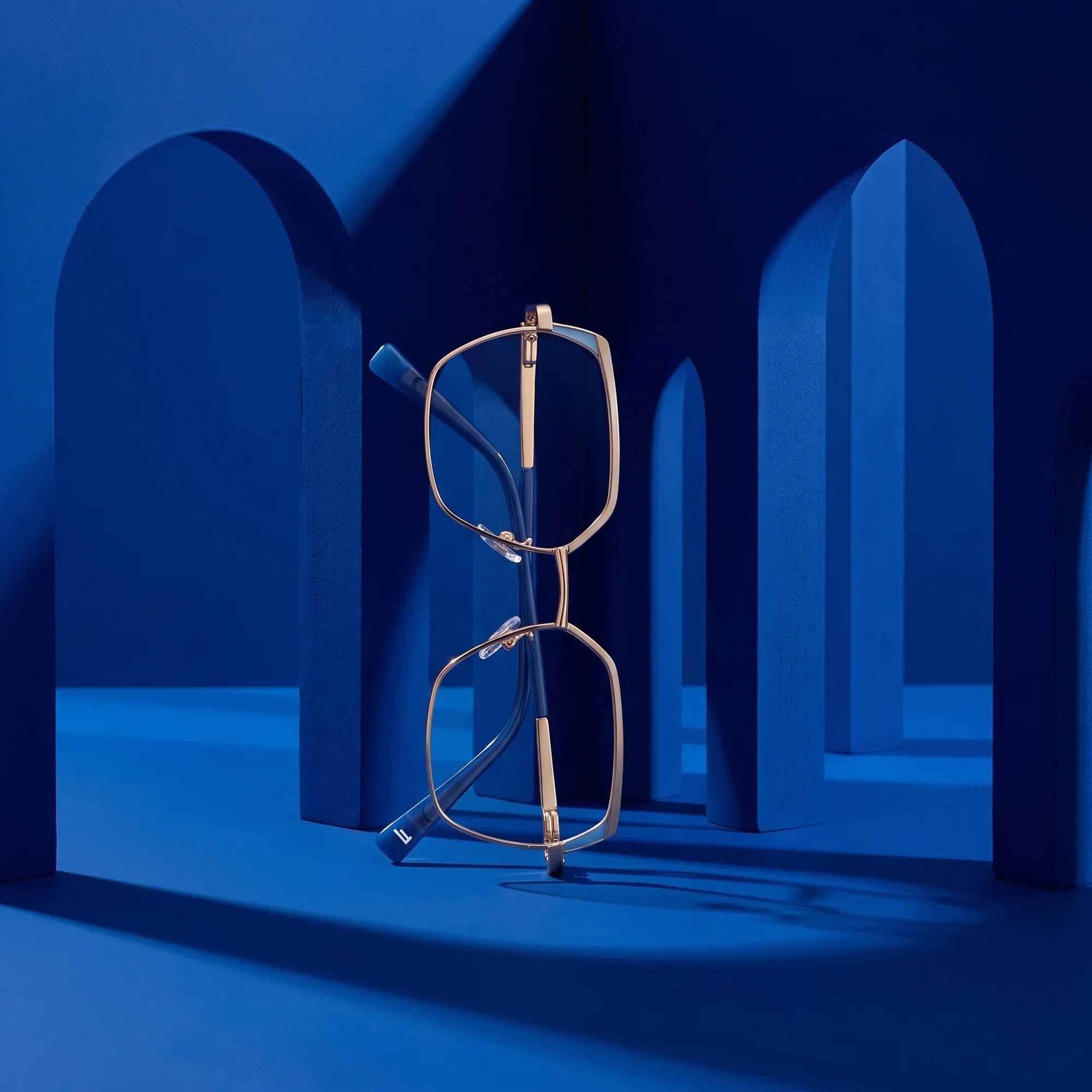 Anteojos Fiore 3971 en grey gold – staged on a sculptural cobalt architecture set