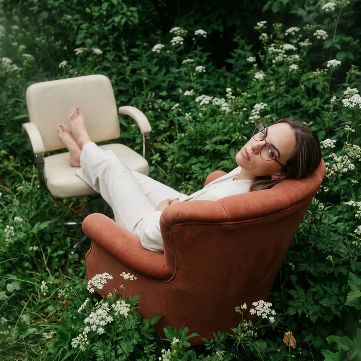 Anteojos Fiore 3983 en red black, en modelo – retrato de campaña, lounging in an armchair in a wildflower meadow