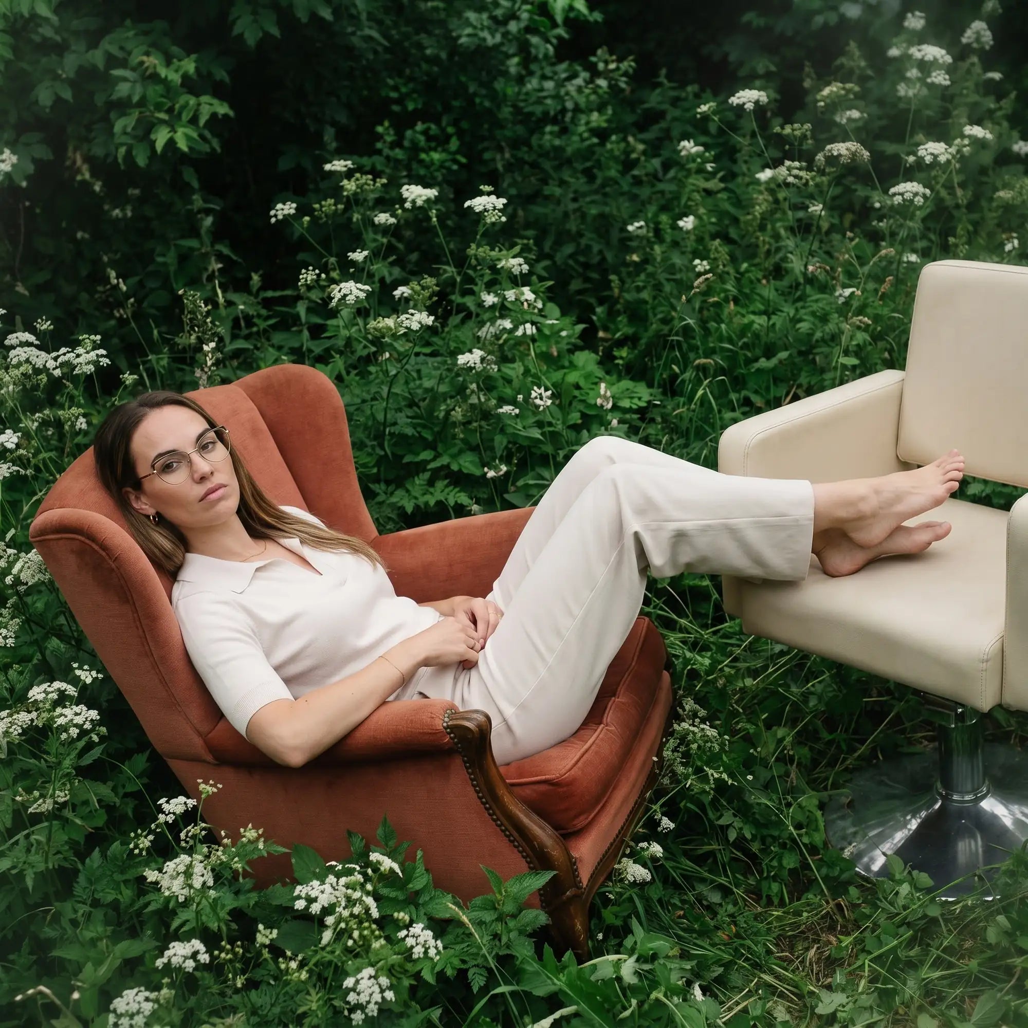 Anteojos Fiore 3983 en brown gold, en modelo – retrato de campaña, lounging in an armchair in a wildflower meadow