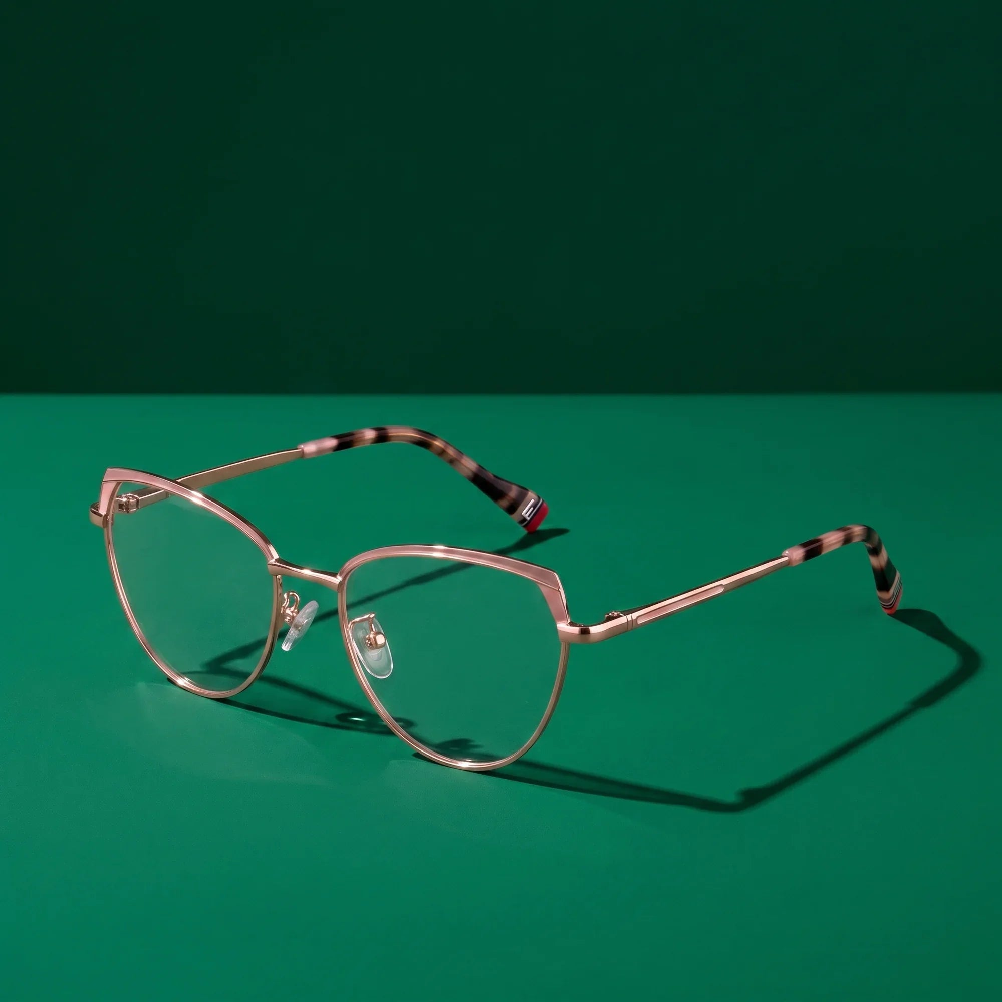 Anteojos Fiore 3983 en pink gold – bodegón editorial sobre un set esmeralda saturado