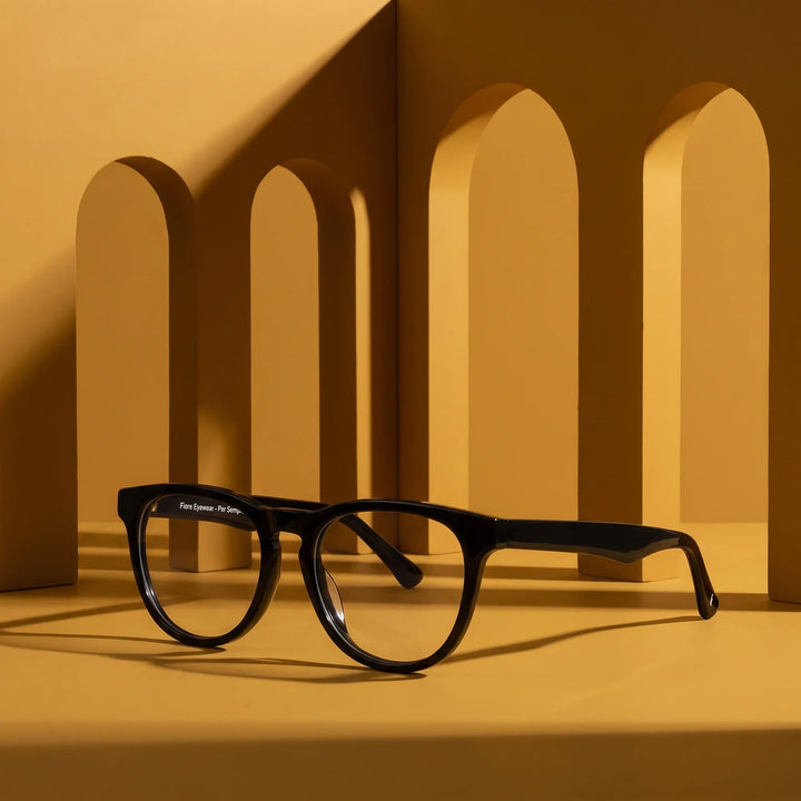 Anteojos Fiore 4488 en negro – displayed on a mustard ochre podium among arches