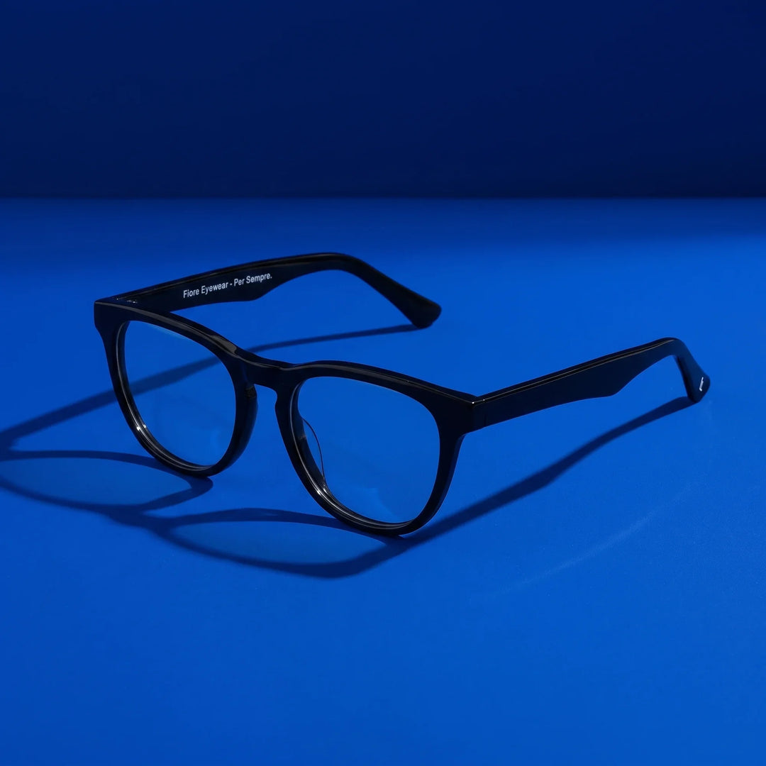 Anteojos Fiore 4488 en negro – hero still life against a deep cobalt backdrop