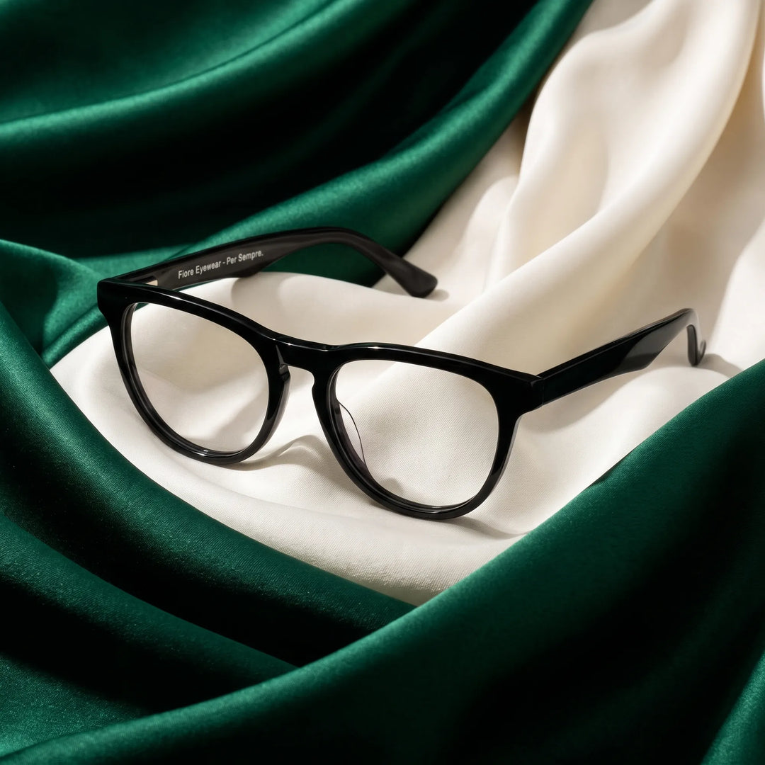 Anteojos Fiore 4488 en negro – resting on draped emerald and ivory silk