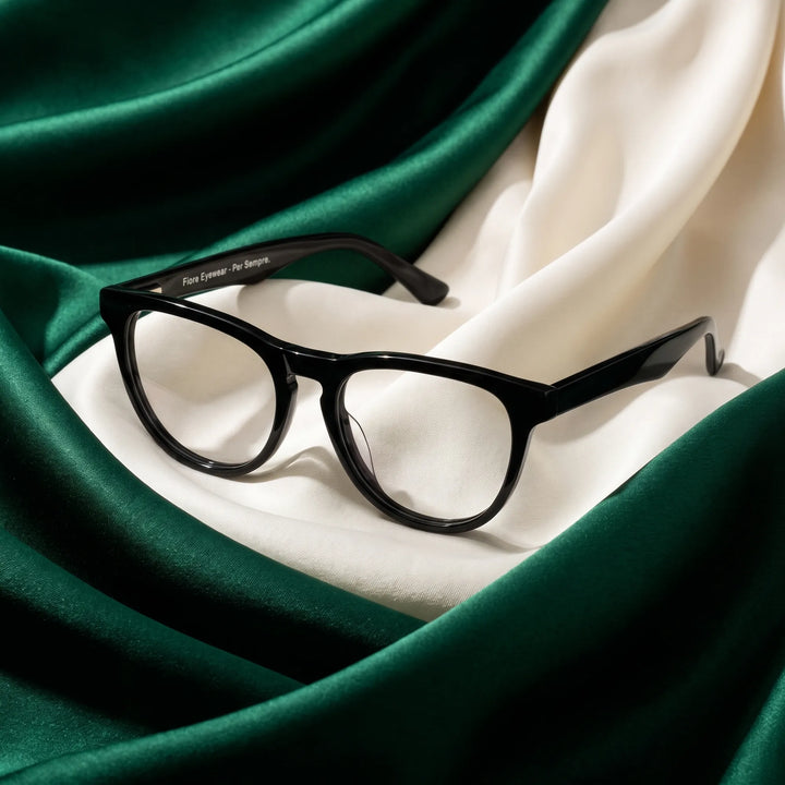 Anteojos Fiore 4488 en negro – resting on draped emerald and ivory silk