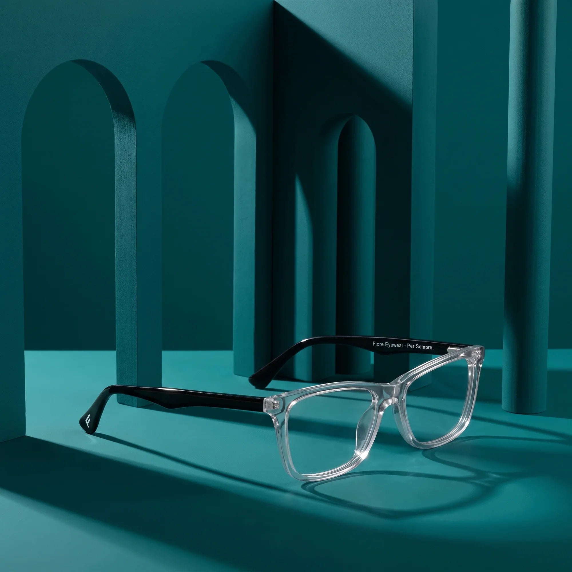Anteojos Fiore 5228 en transparent – staged on a sculptural teal architecture set