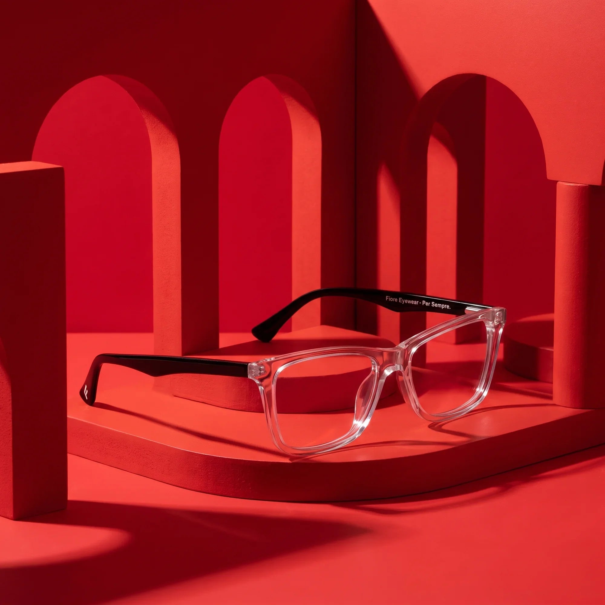 Anteojos Fiore 5228 en transparent – displayed on a vivid red podium among arches