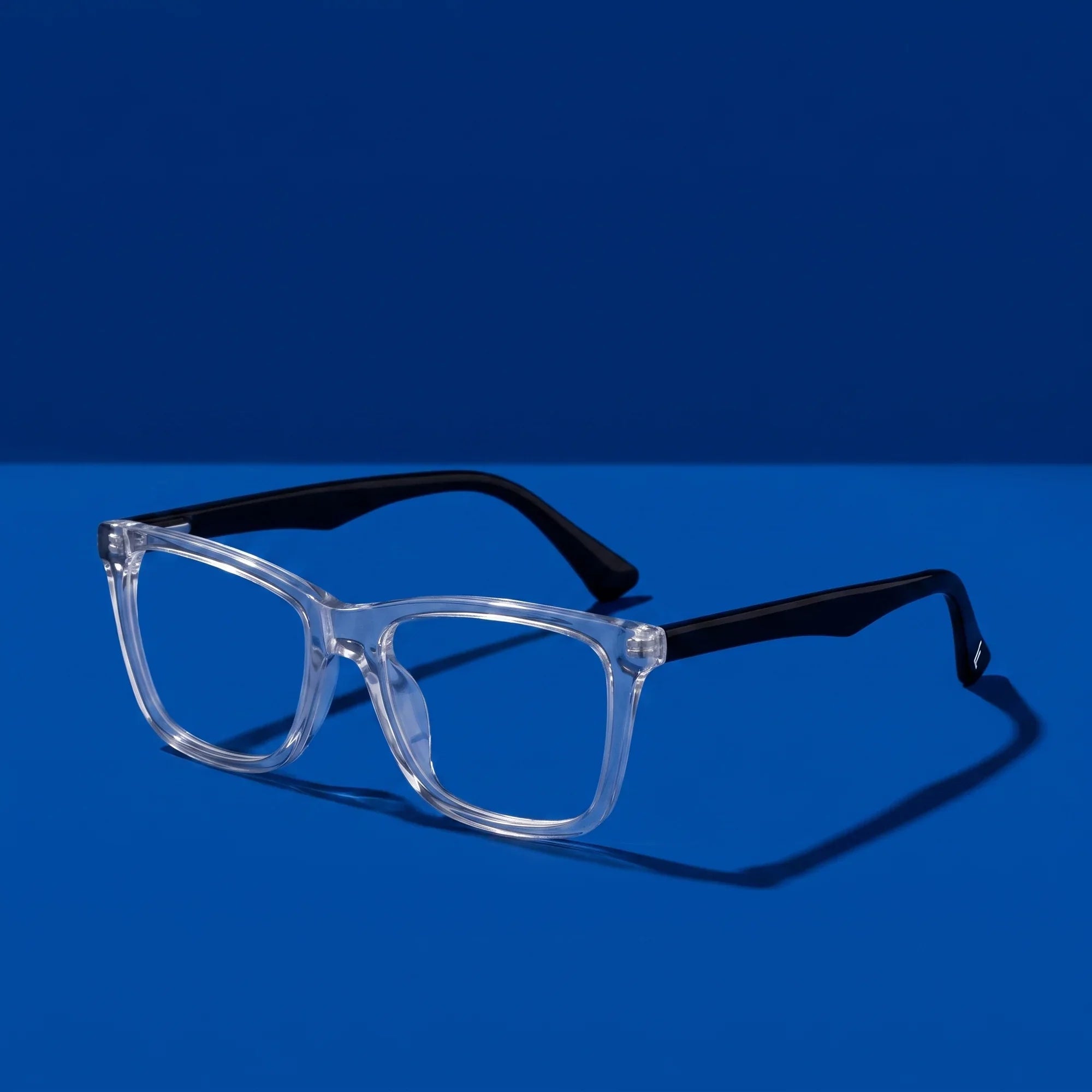 Anteojos Fiore 5228 en transparent – hero still life against a deep cobalt backdrop