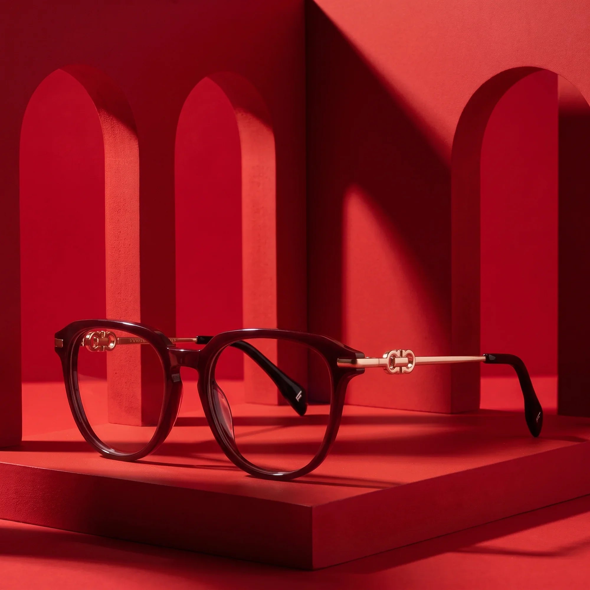 Anteojos Fiore 5409 en brown red – displayed on a vivid red podium among arches