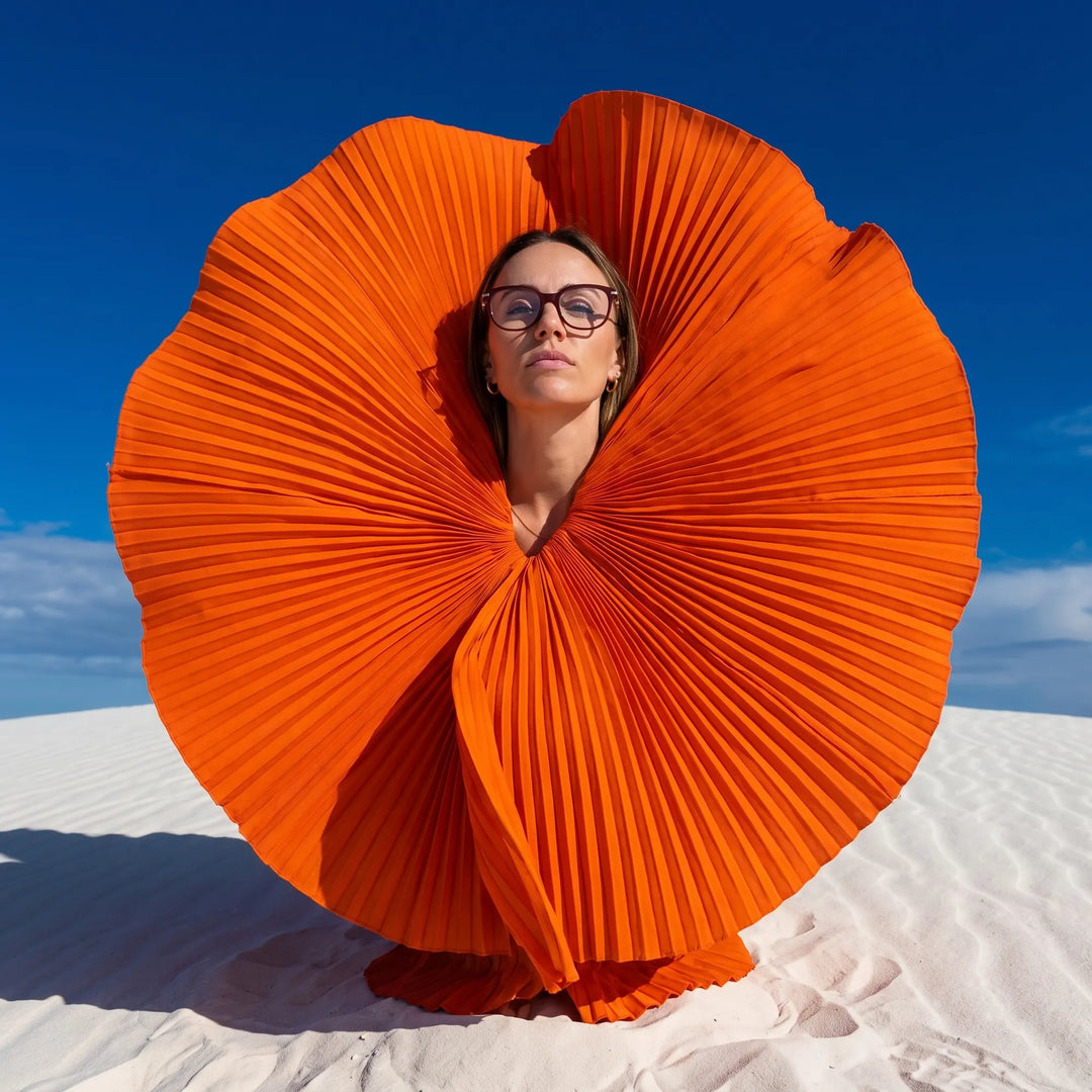 Anteojos Fiore 5409 en brown red, en modelo – retrato de campaña, abanico plisado naranja escultórico sobre dunas blancas