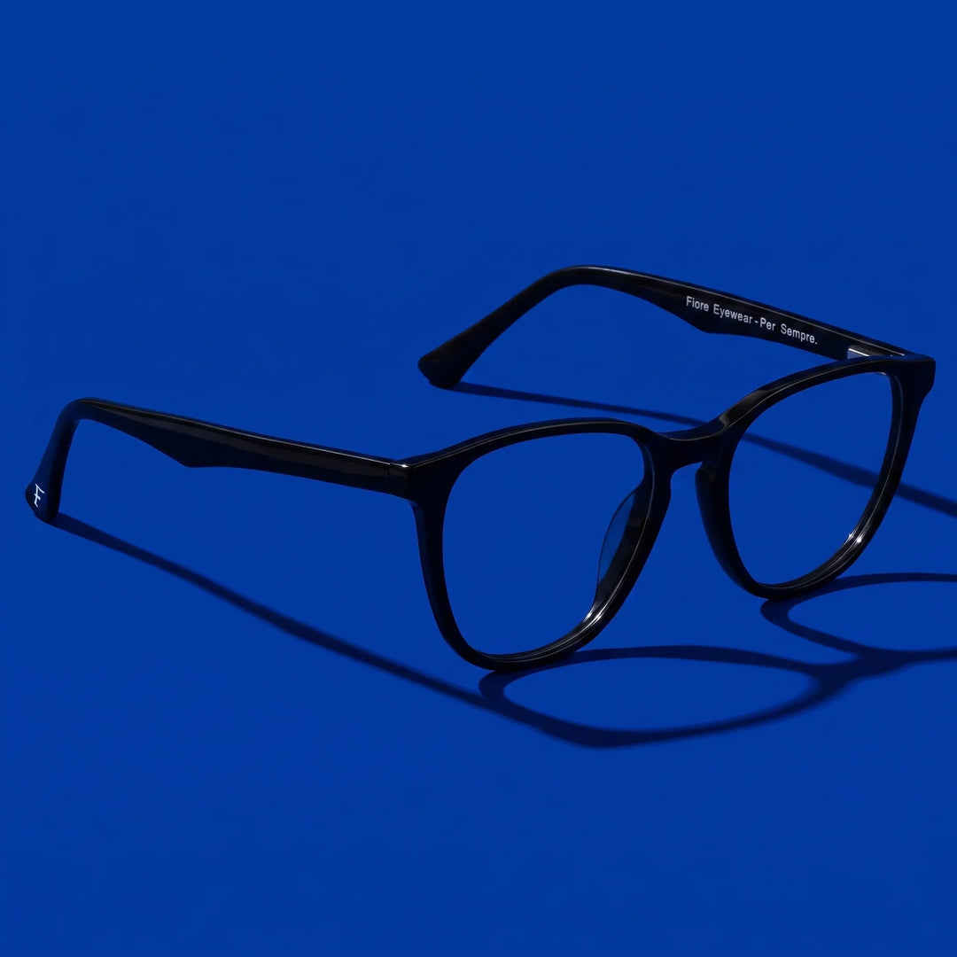 Anteojos Fiore 7046 en negro – hero still life against a deep cobalt backdrop