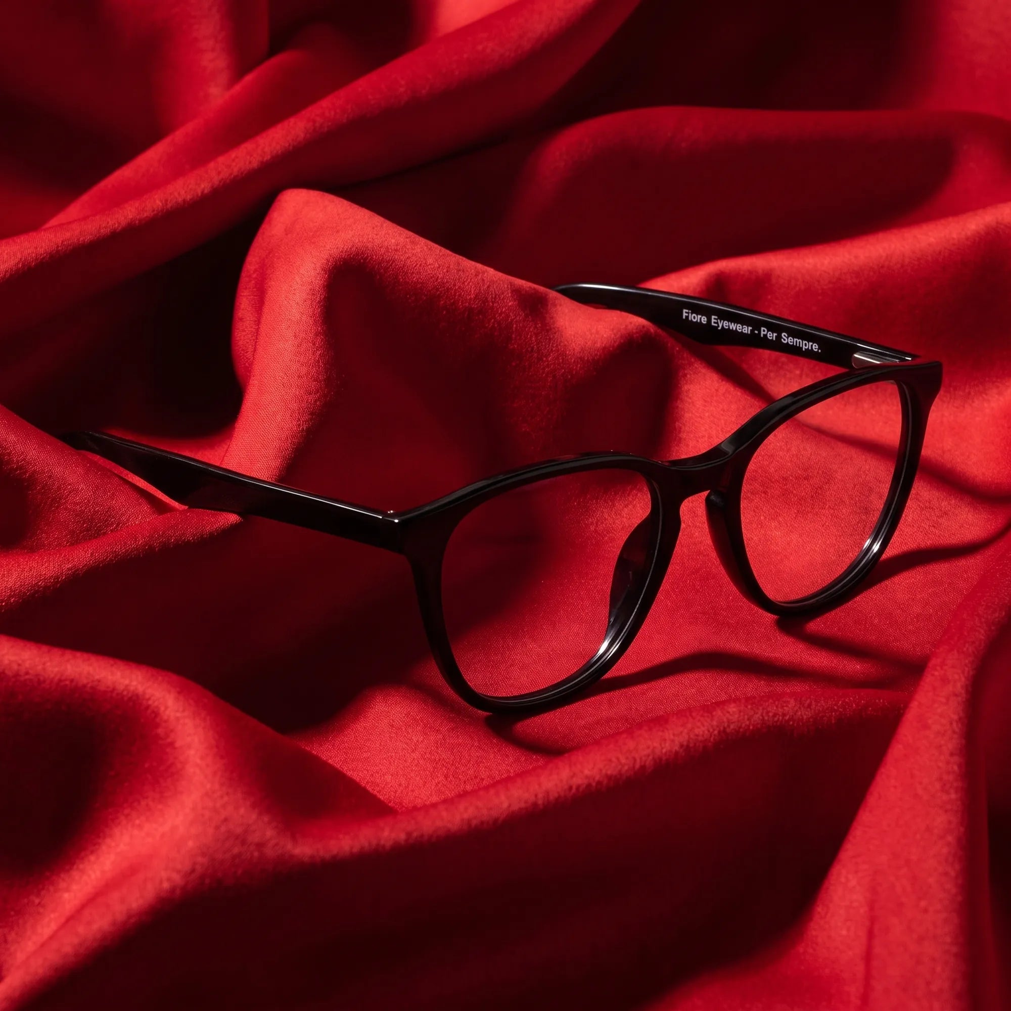 Anteojos Fiore 7046 en negro – nested in flowing vivid red silk